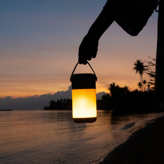 Person holding a VQ Halo as a lantern by the beach at sunset